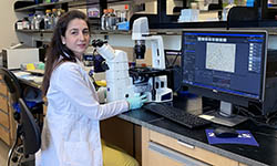Jezabel Blanco sits at a microscope in her lab